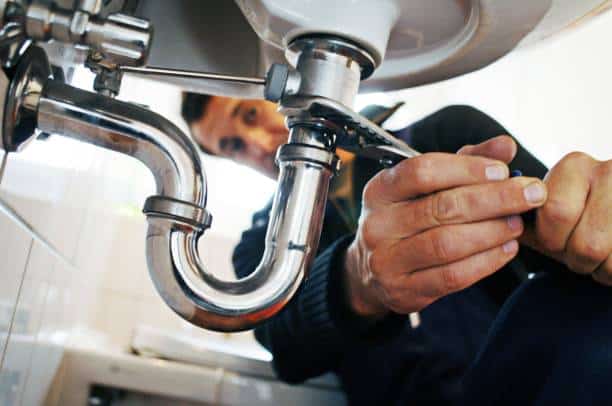 A plumber performing service on a pipe with a wrench