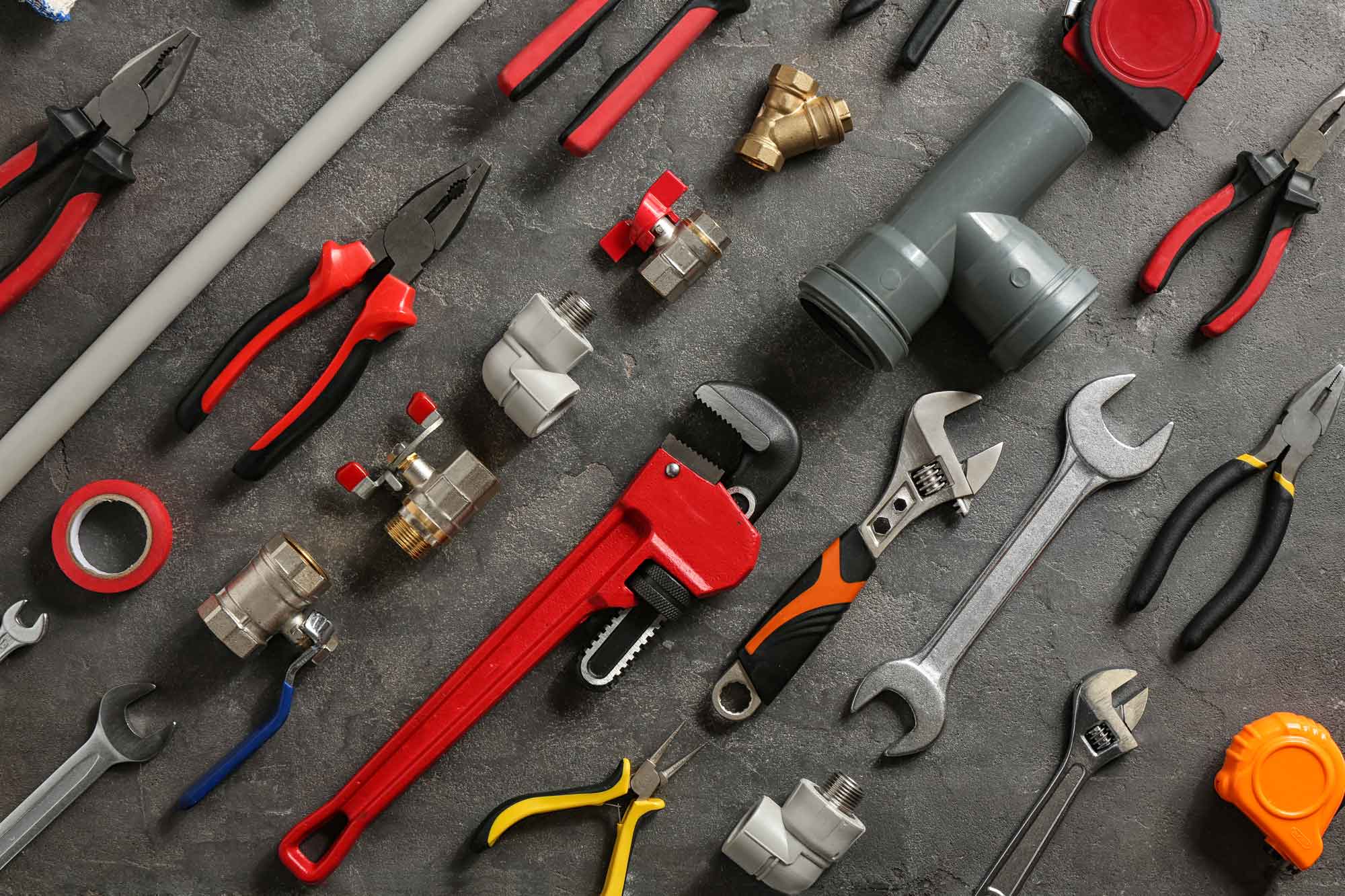 An assortment of plumbing tools laid out on the ground